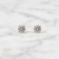 10K yellow gold 3mm round CZ stud earrings in polished four-prong settings on white marble surface