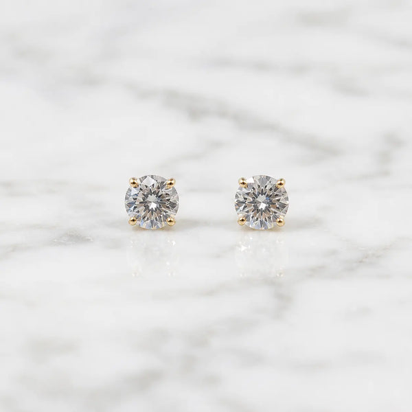 10K yellow gold 3mm round CZ stud earrings in polished four-prong settings on white marble surface
