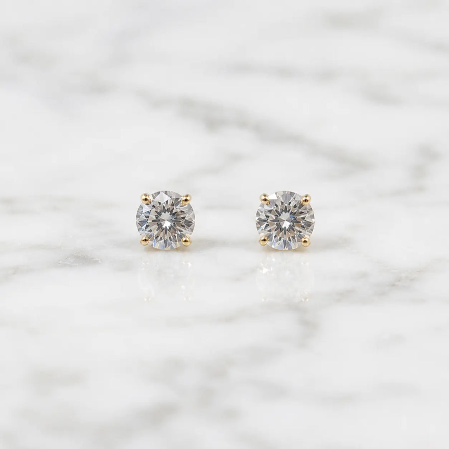 10K yellow gold 3mm round CZ stud earrings in polished four-prong settings on white marble surface