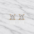 10K yellow gold 4mm princess-cut CZ stud earrings in four-prong settings on white marble surface