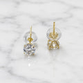 10K yellow gold 5mm round CZ stud earrings showing side and back view with push-back posts on marble surface