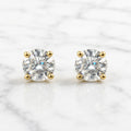 10K yellow gold 6mm round CZ stud earrings in polished four-prong settings on white marble surface