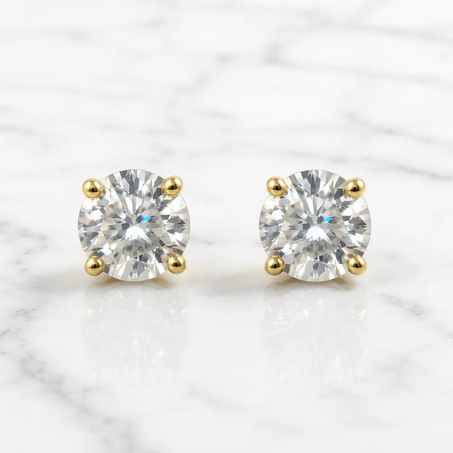 10K yellow gold 6mm round CZ stud earrings in polished four-prong settings on white marble surface