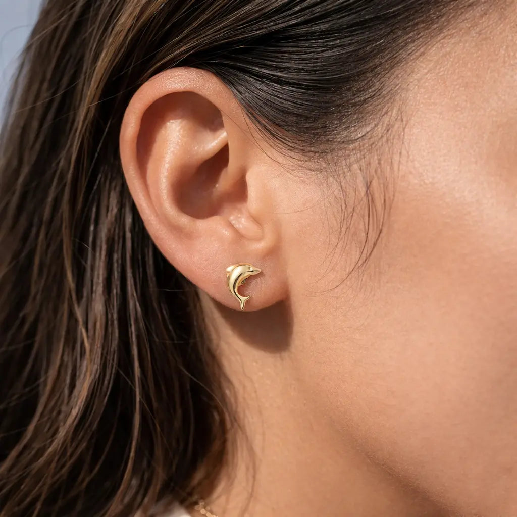 14K yellow gold dolphin stud earrings worn on ear with polished finish everyday jewelry gift idea