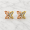 14K tri-color gold butterfly stud earrings with rose, yellow, and white gold details on marble surface