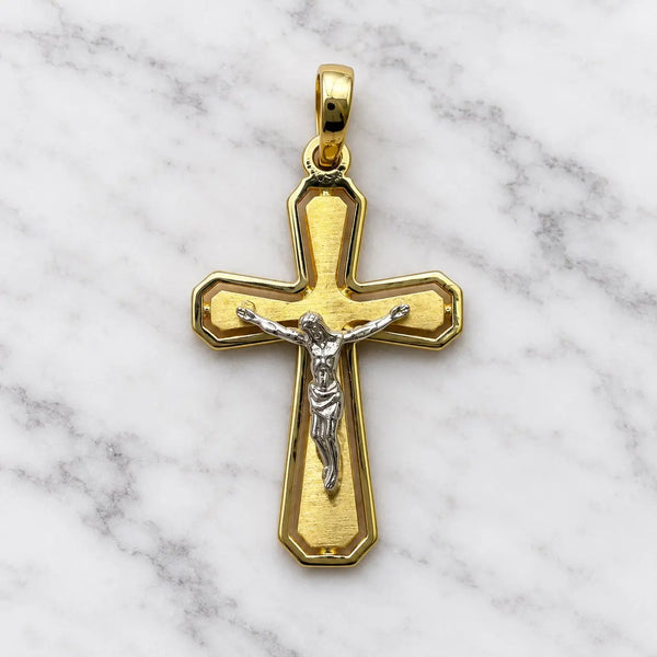 14K two-tone gold crucifix pendant with white gold corpus on brushed yellow gold cross on white marble surface