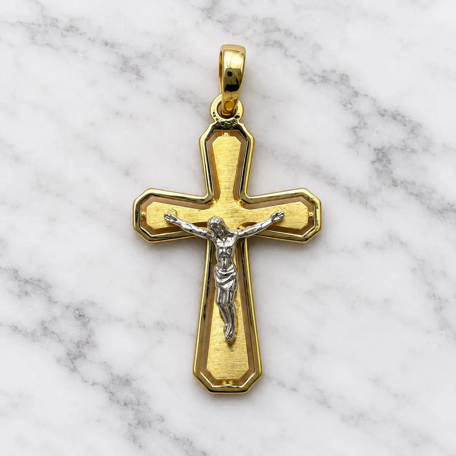 14K two-tone gold crucifix pendant with white gold corpus on brushed yellow gold cross on white marble surface