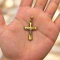 14K two-tone gold crucifix pendant with white gold corpus resting in an open palm showing its size and scale