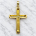 Back view of 14K two-tone gold cross pendant showing hollow recessed construction on white marble surface