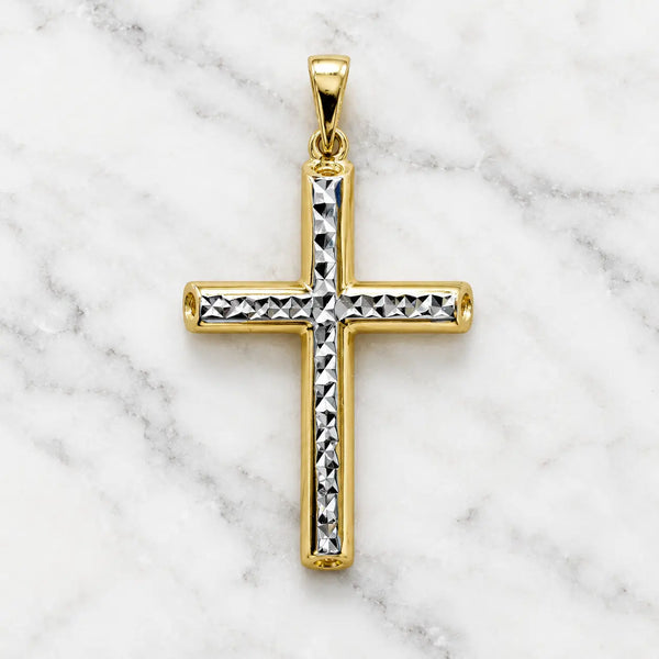 14K two-tone gold diamond-cut cross pendant with white gold faceted center strip on white marble surface