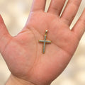 14K two-tone gold diamond-cut cross pendant resting in an open palm showing its size and scale