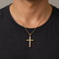 14K two-tone gold diamond-cut cross pendant worn on a gold cable chain over a black crew-neck shirt
