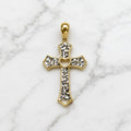 14K two-tone gold diamond-cut cross pendant with white gold accents and open-heart center on marble surface