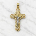 Front of a 14K two-tone gold filigree crucifix pendant with a white gold corpus and diamond-cut panels