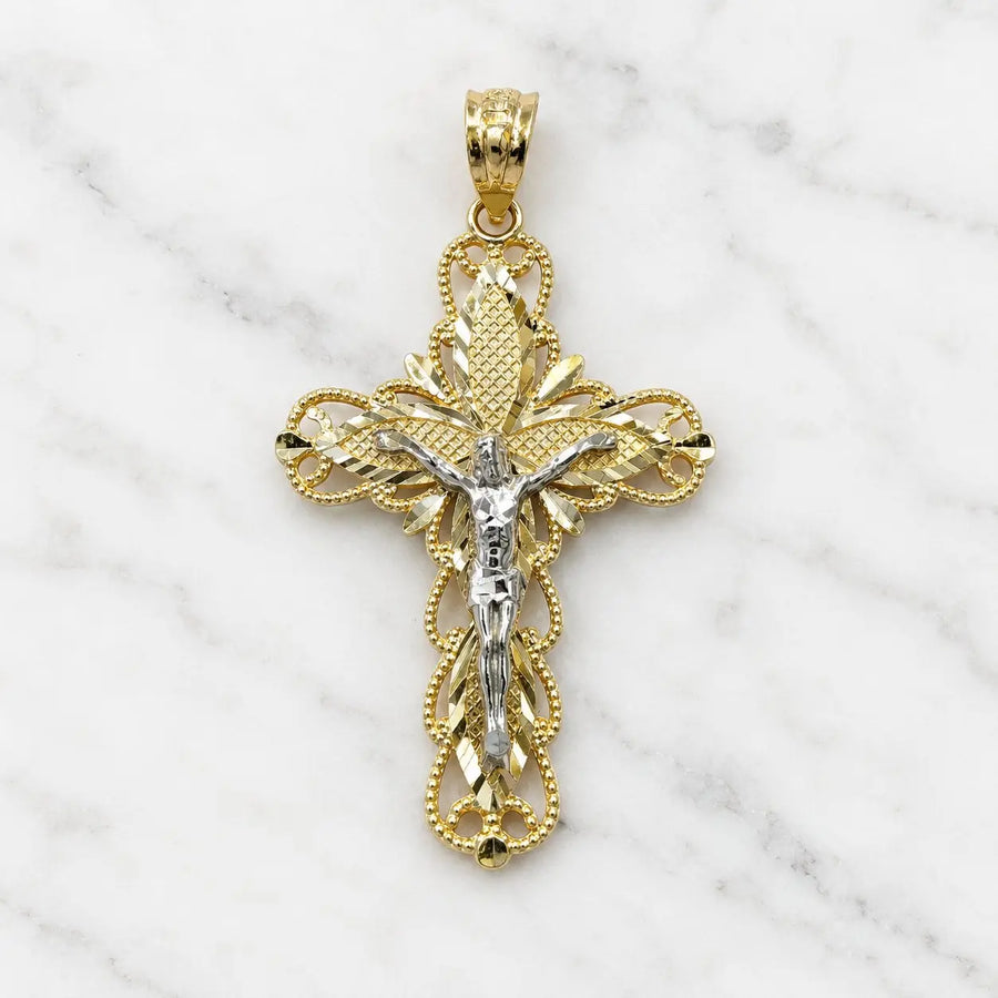 Front of a 14K two-tone gold filigree crucifix pendant with a white gold corpus and diamond-cut panels