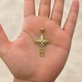 14K two-tone gold filigree crucifix pendant with white gold corpus held in an open palm to show its size