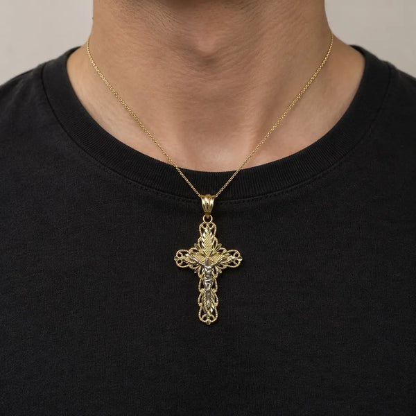 14K two-tone gold filigree crucifix pendant with white gold corpus worn on a gold cable chain over a black crew-neck shirt