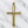 Back view of 14K two-tone gold flared cross pendant showing smooth polished concave arms on white marble surface