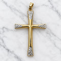 14K two-tone gold flared cross pendant with white gold diamond-cut panels at the arm ends on white marble surface