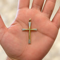 14K two-tone gold flared diamond-cut cross pendant resting in an open palm showing its size and scale