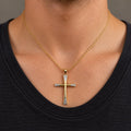 14K two-tone gold flared diamond-cut cross pendant worn on a gold cable chain over a black crew-neck shirt