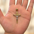 14K two-tone gold crucifix pendant with white gold corpus held in an open palm to show its size