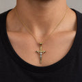 14K two-tone gold crucifix pendant with white gold corpus worn on a gold cable chain over a black crew-neck shirt