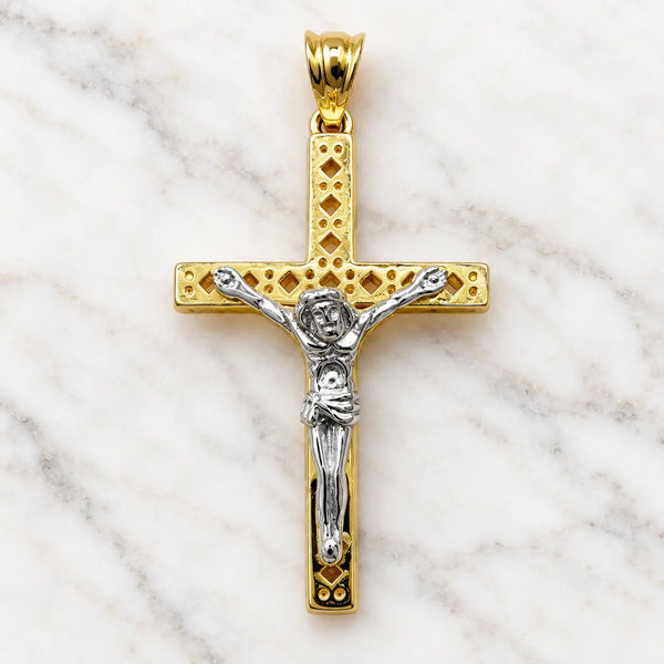 14K two-tone gold crucifix pendant with white gold corpus on pierced diamond-pattern cross on white marble surface