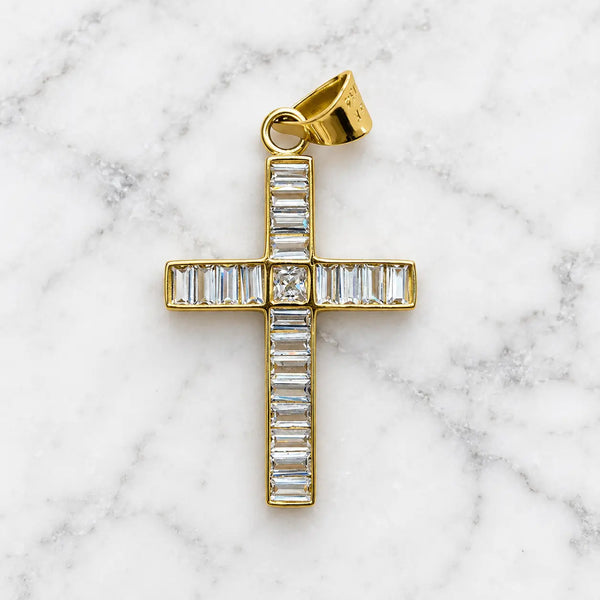 14K yellow gold baguette CZ cross pendant with princess-cut center stone on white marble surface