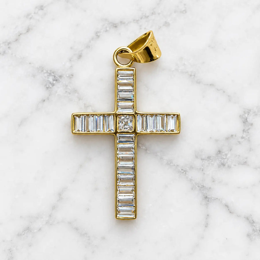 14K yellow gold baguette CZ cross pendant with princess-cut center stone on white marble surface