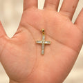 14K yellow gold baguette CZ cross pendant resting in an open palm showing its size and scale