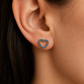 14K yellow gold blue CZ open heart stud earring worn on ear showing petite scale and color