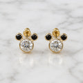 14K yellow gold mouse ear stud earrings with clear and black CZ stones on marble surface