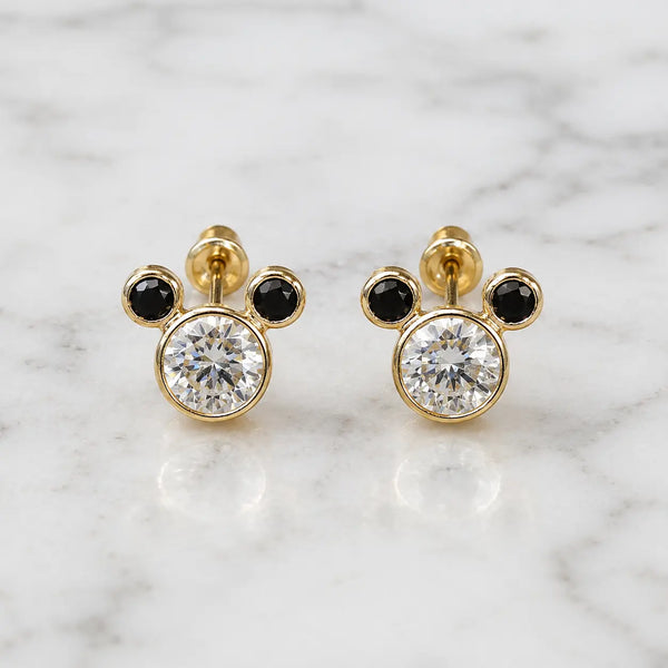 14K yellow gold mouse ear stud earrings with clear and black CZ stones on marble surface