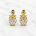 14K yellow gold owl screw back stud earrings with heart-shaped clear CZ body on marble surface