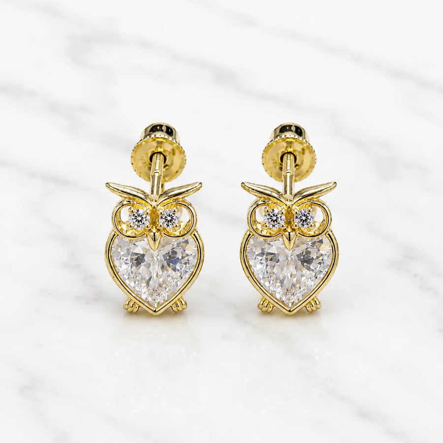 14K yellow gold owl screw back stud earrings with heart-shaped clear CZ body on marble surface