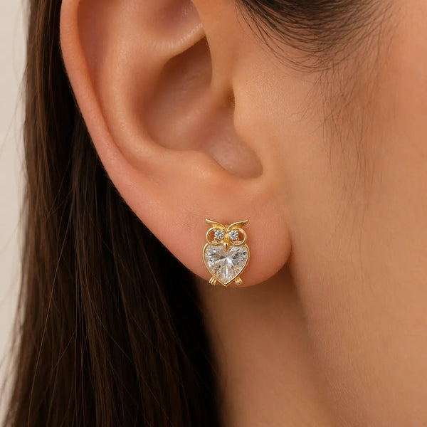 14K yellow gold CZ owl stud earring worn on ear showing petite heart-shaped design and scale
