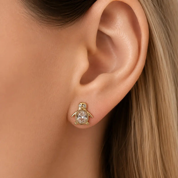 14K yellow gold CZ penguin stud earring worn on ear showing petite oval body design and scale