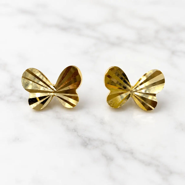 14K yellow gold diamond-cut butterfly stud earrings with faceted polished wings on marble surface