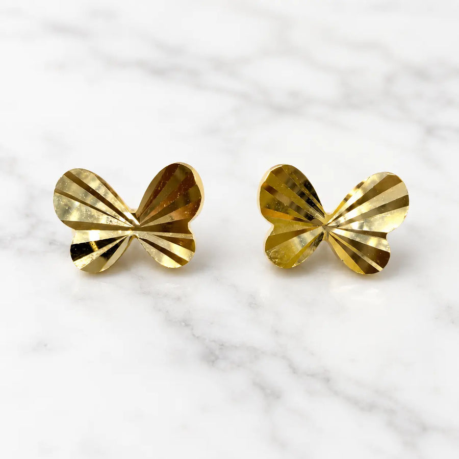 14K yellow gold diamond-cut butterfly stud earrings with faceted polished wings on marble surface