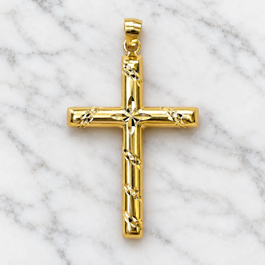 14K yellow gold diamond-cut cross pendant with starburst center and polished tubular arms on white marble surface
