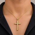 14K yellow gold diamond-cut cross pendant worn on a gold cable chain at a man's neckline over a black polo shirt
