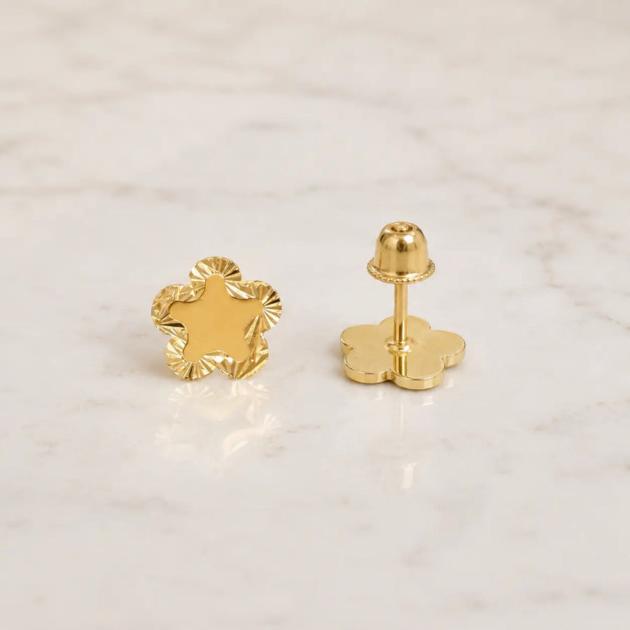 14K yellow gold diamond-cut flower stud earrings shown front and back on marble surface