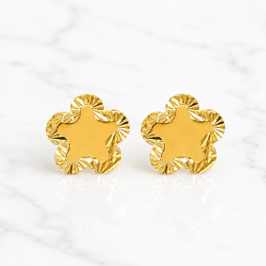 14K yellow gold diamond-cut flower stud earrings with scalloped polished petals on marble surface