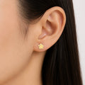 14K yellow gold diamond-cut flower stud earring worn on ear showing petite everyday fit