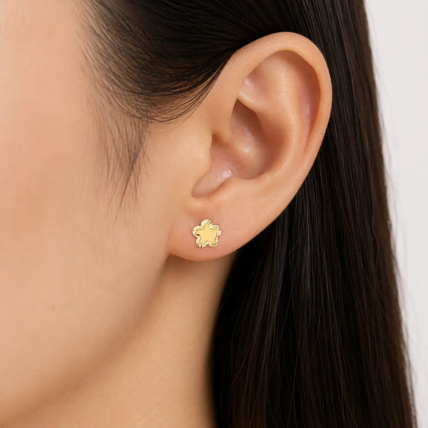 14K yellow gold diamond-cut flower stud earring worn on ear showing petite everyday fit