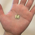 14K yellow gold Holy Bible pendant held in an open palm to show its small size