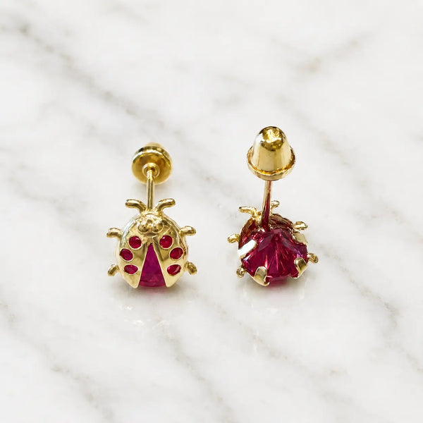 14K yellow gold ladybug stud earrings with red CZ body and wing stones shown front view on marble surface
