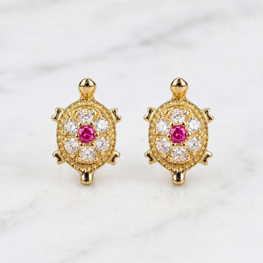 14K yellow gold turtle stud earrings with pink center CZ and clear CZ accents on marble surface