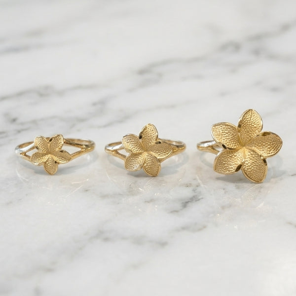 14K yellow gold plumeria flower rings in small medium and large sizes side by side on white background